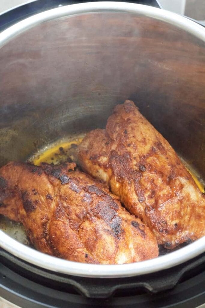 Two pork pieces being fried in an Instant Pot.