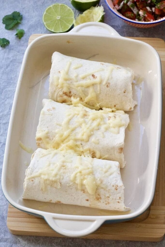 Three pulled pork burritos in a baking dish with cheese.