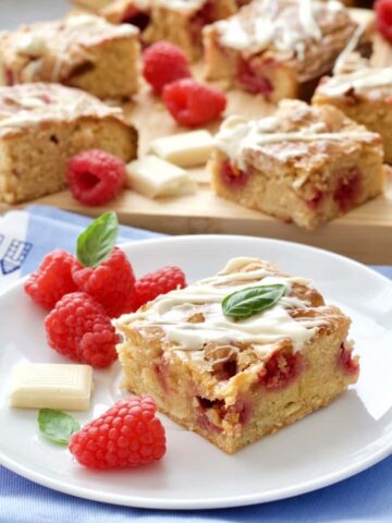 Blondie square on a plate with fresh raspberries.