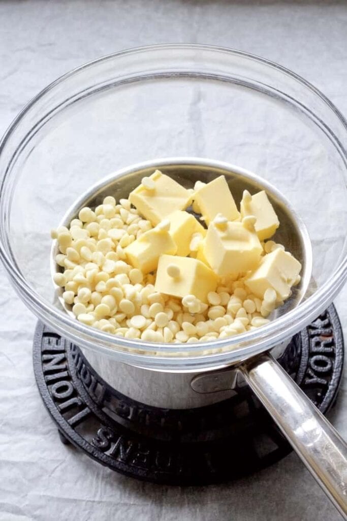 White chocolate and butter in a bowl sitting over a pan.