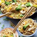 Chicken chow mein in a pan and portions in bowls.