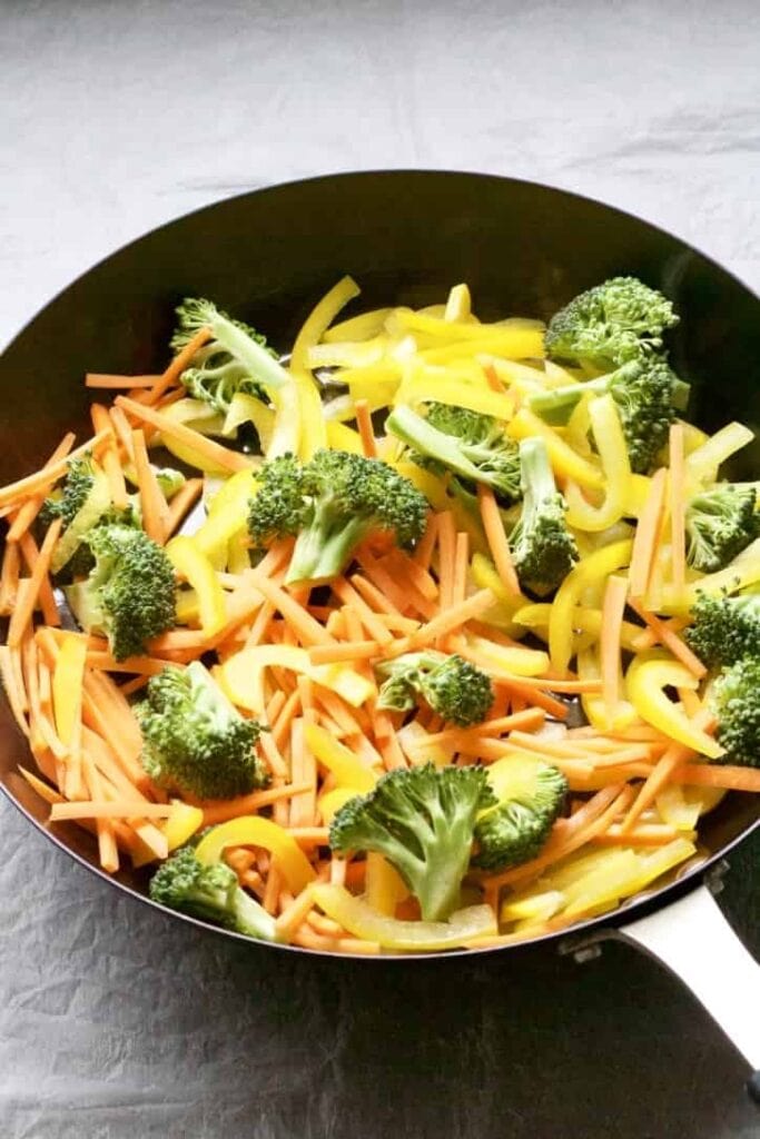 Carrot matchsticks, sliced yellow pepper & broccoli in a pan.