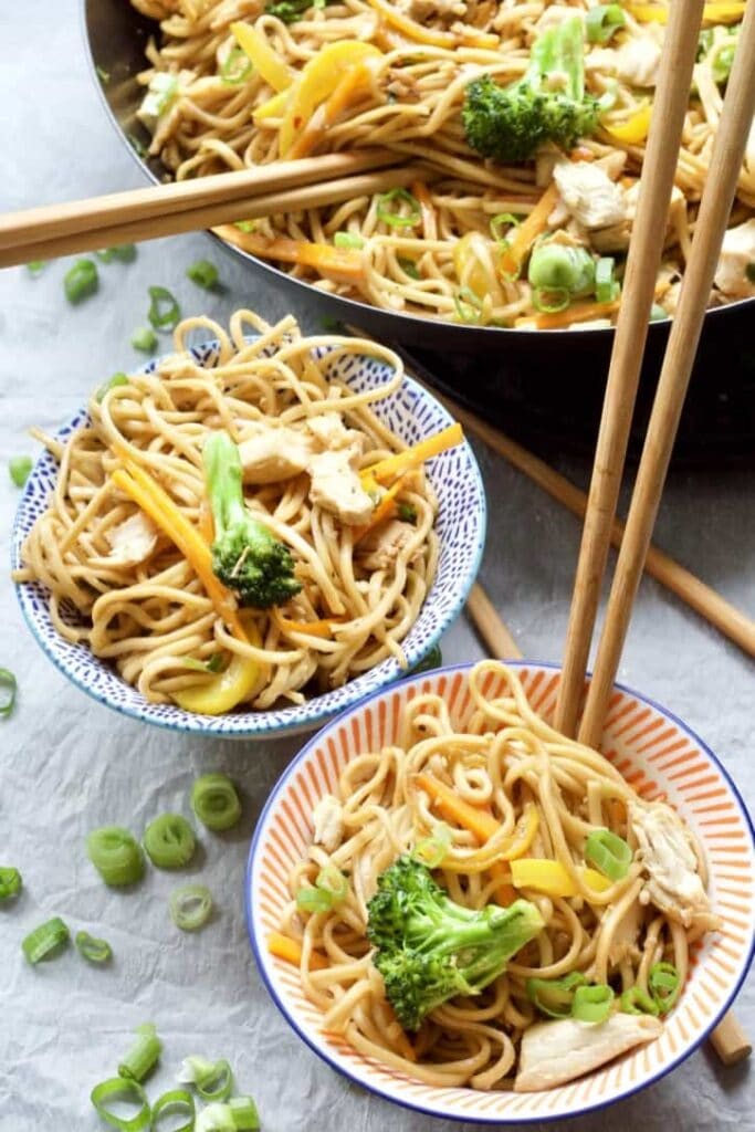 Chicken chow mein in bowls with chopsticks.