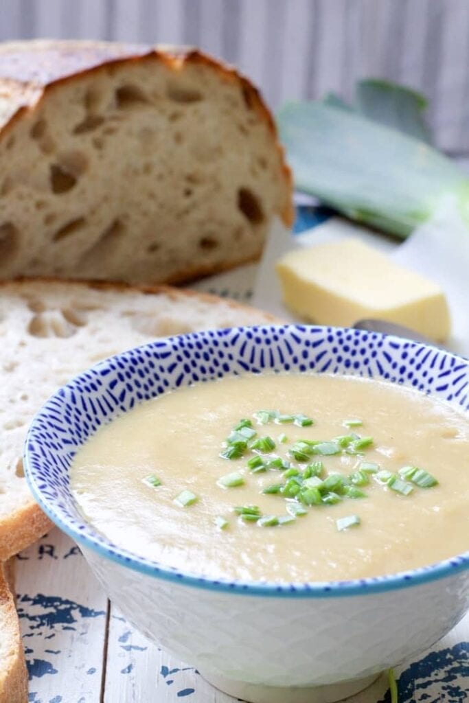 Bowl of soup with bread in the background.