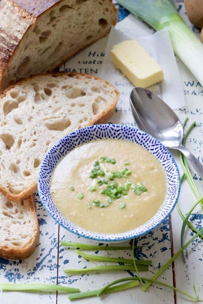 Bowl of leek & potato soup with bread, butter and chives.