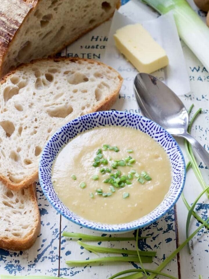 Bowl of leek & potato soup with bread, butter and chives.