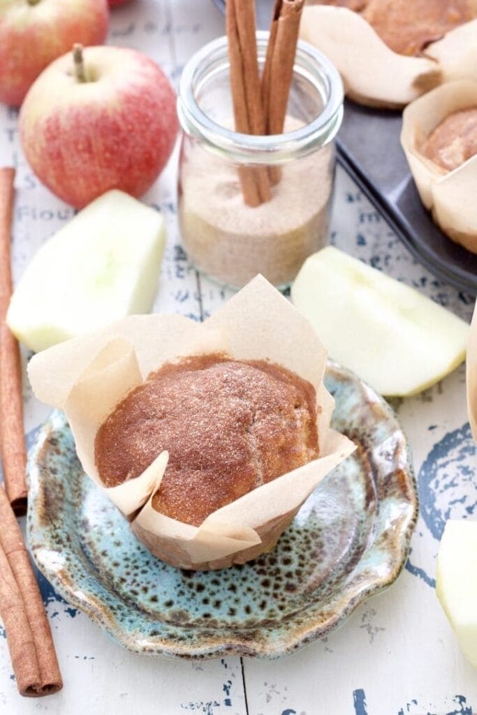 Apple & cinnamon muffin on a plate with apple chunks around it.