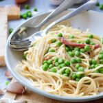 Spaghetti carbonara plated up with cutlery.