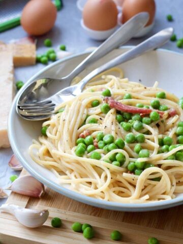 Spaghetti carbonara plated up with cutlery.