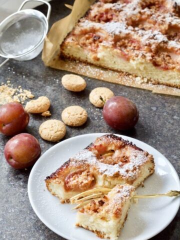 Plum and almond cake with plums and amaretti biscuits around it.