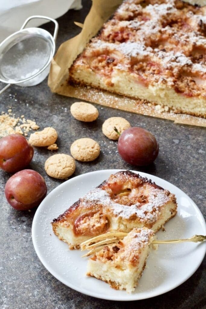 Plum and almond cake with plums and amaretti biscuits around it.