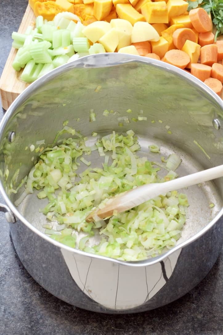 Sliced leek being sautéed in a large soup pot.