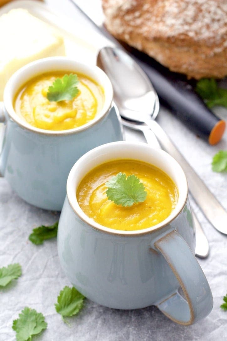 Close up of pumpkin soup with coriander leaf on top.