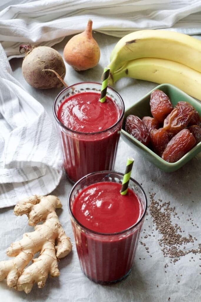 Beetroot smoothie in glasses with ingredients all around.