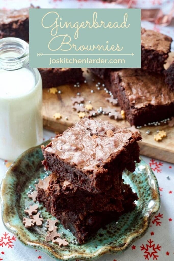 Brownies stacked on a plate with milk & more brownies behind.