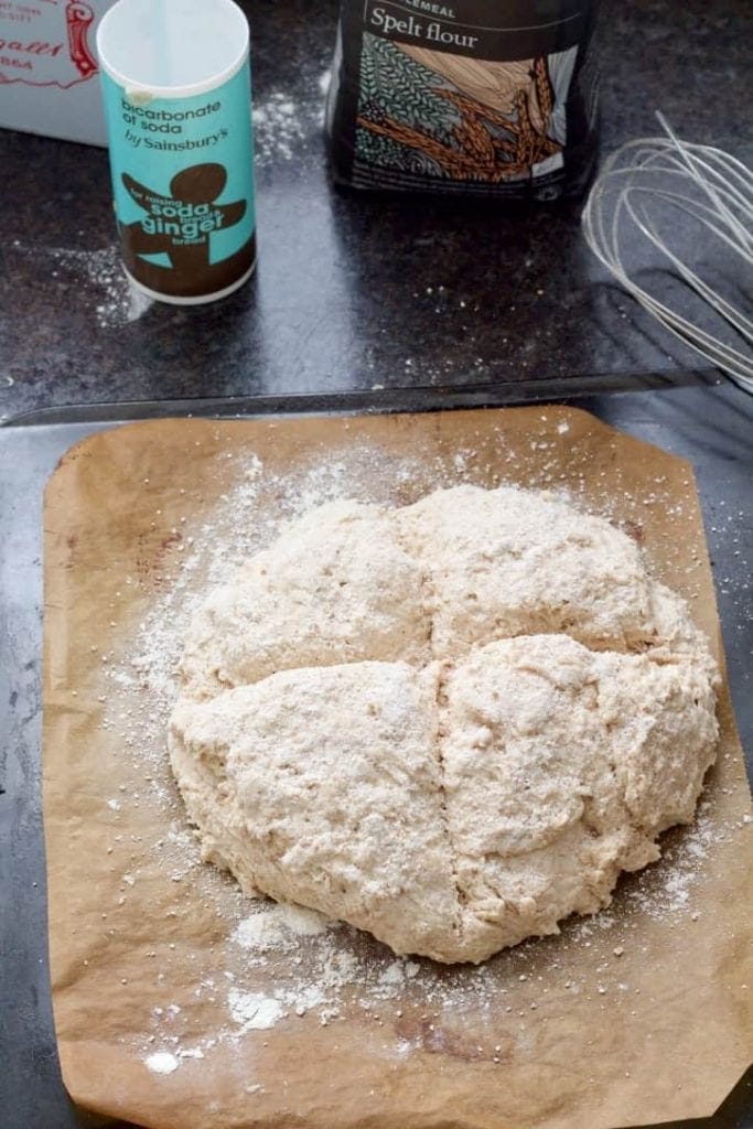 Soda bread dusted with flour on a baking tray.