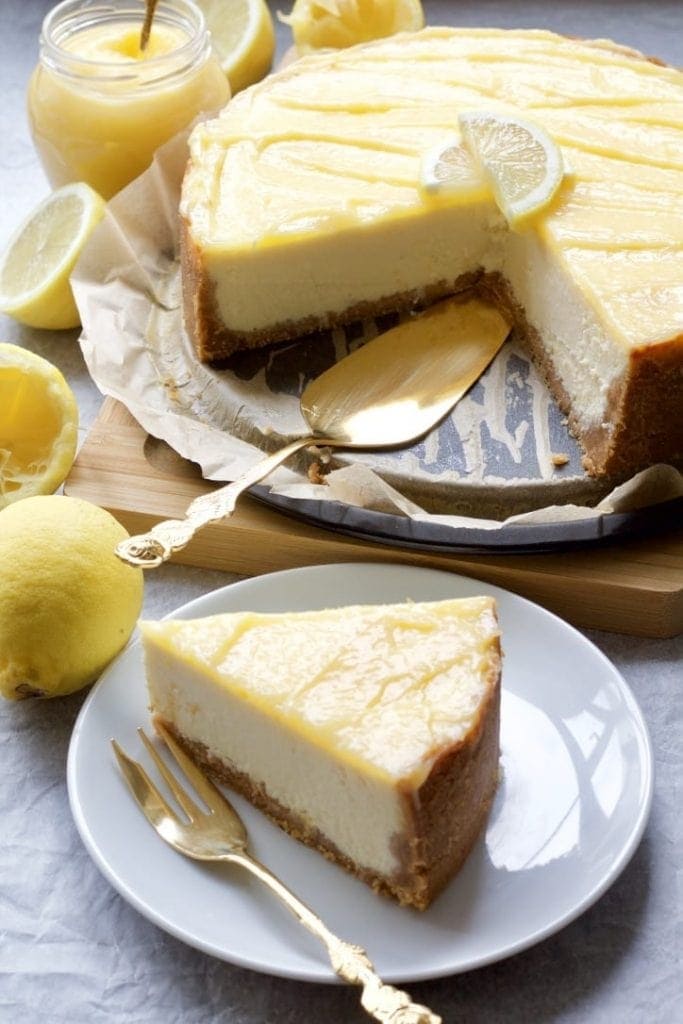 Cheesecake surrounded by lemons and jar of curd.