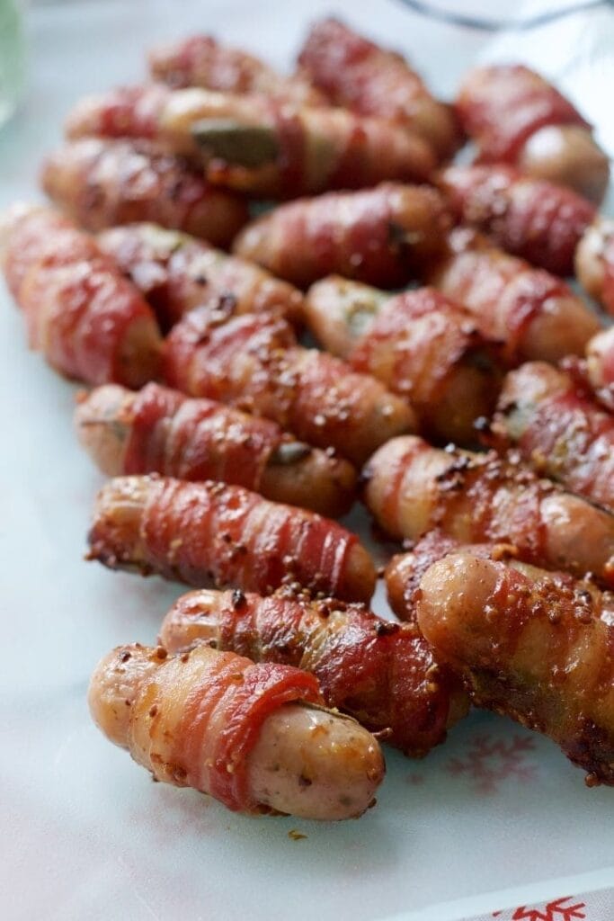 Cooked sausages wrapped in bacon on a platter.