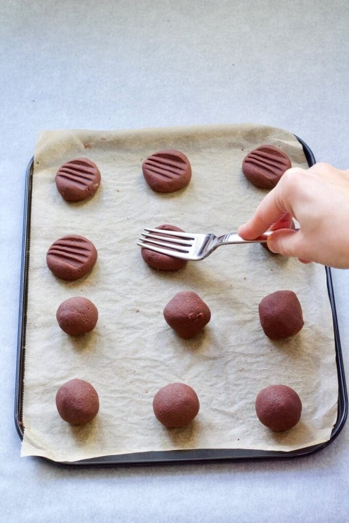 Squashing dough balls with a fork to make a pattern.