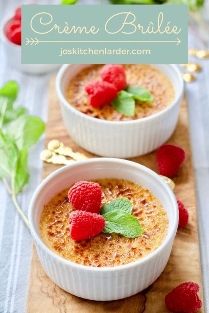 Crème Brûlée with mint and raspberries on a wooden board.