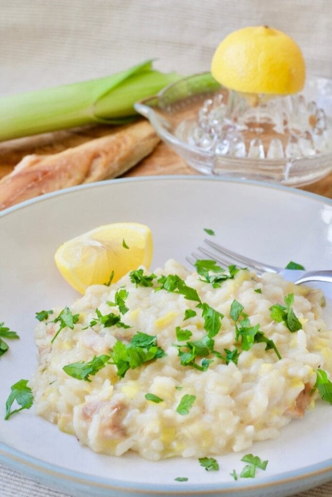 Portion of risotto in a bowl with lemon wedge.