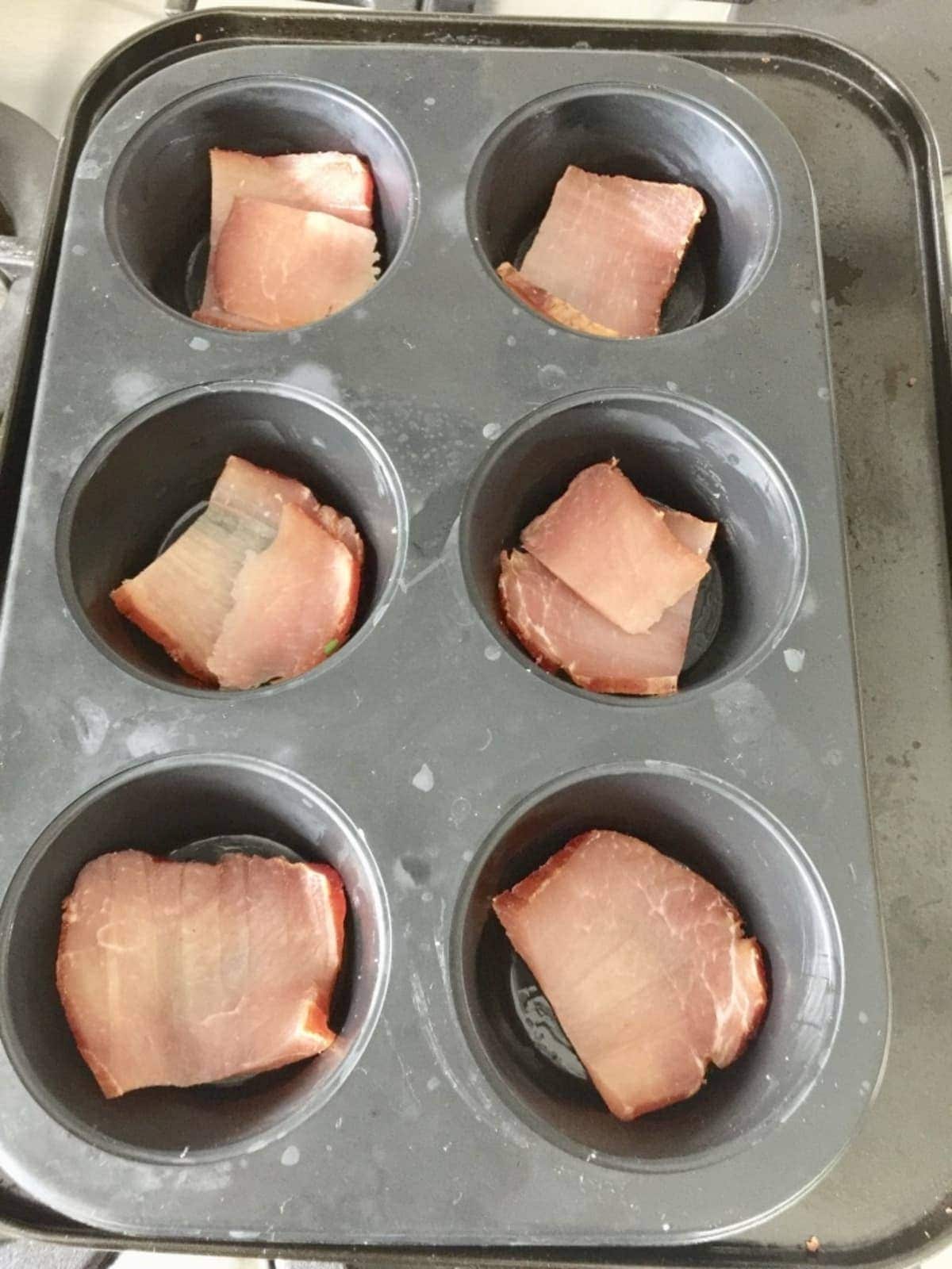 Slices of ham in a muffin tin.