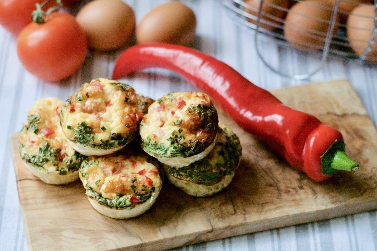 Egg muffins on a wooden board with red pepper.