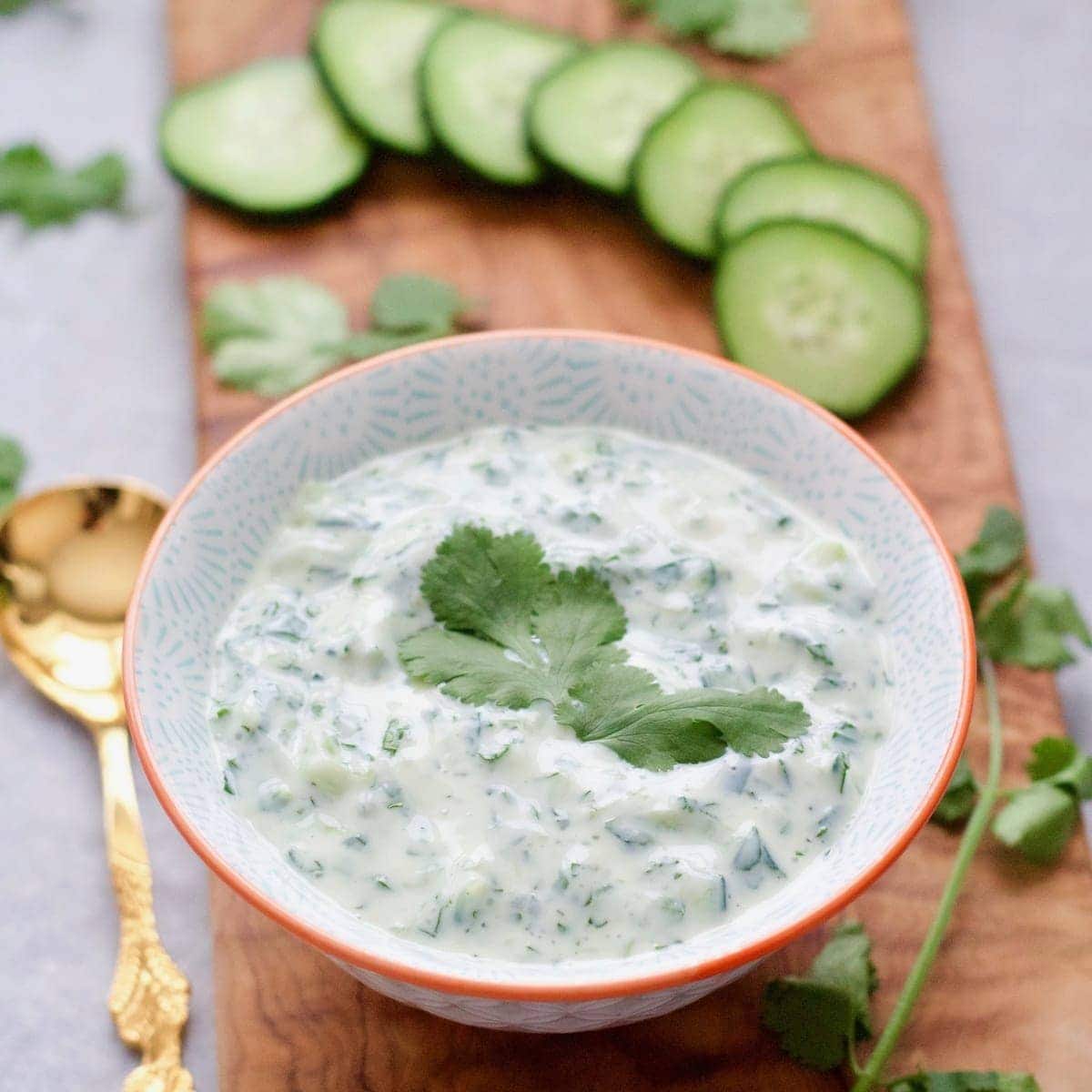 Bowl of cucumber raita garnished with coriander.