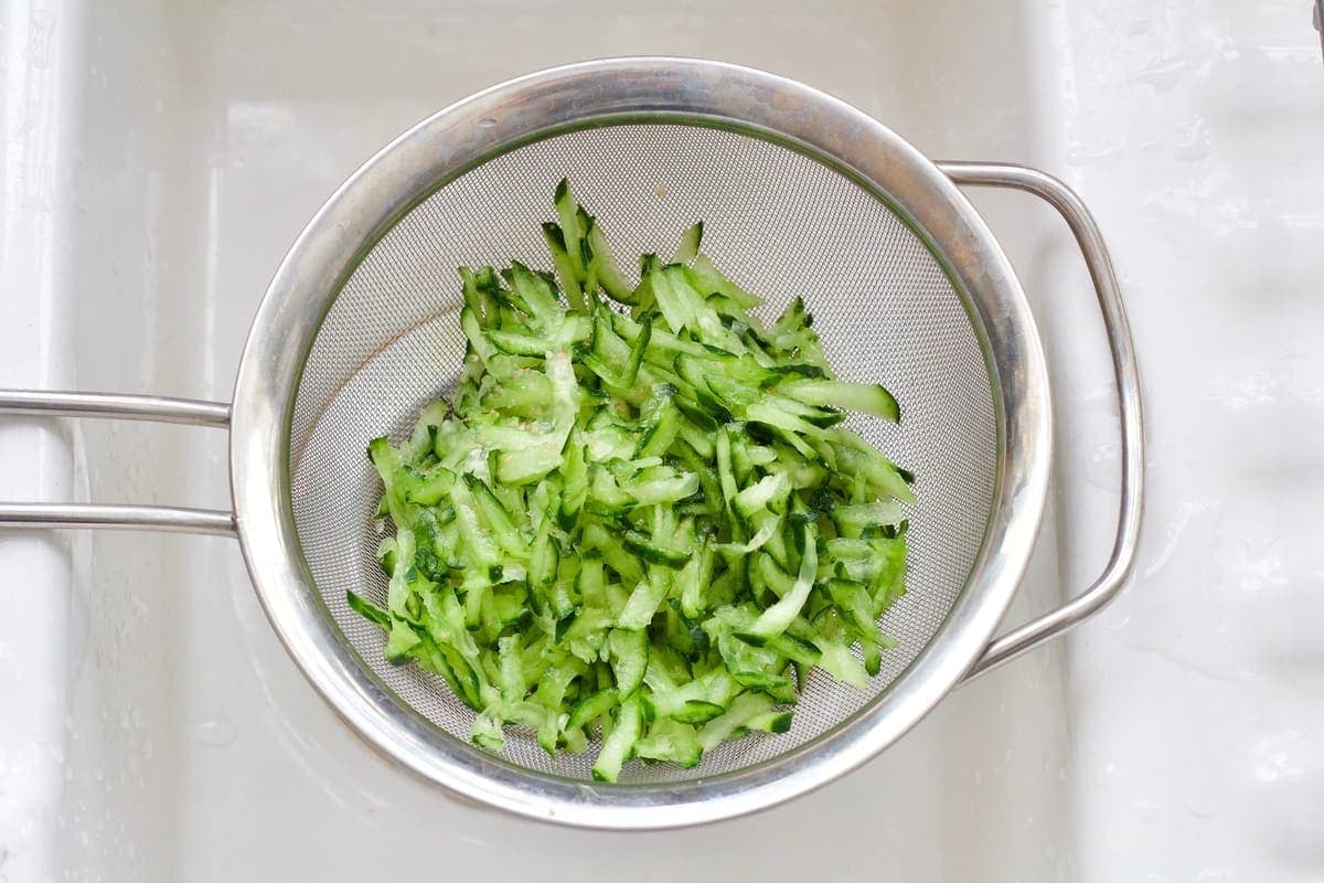 Grated cucumber on a sieve.