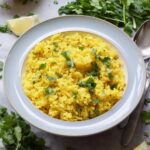 Bowlful of turmeric rice garnished with fresh coriander.