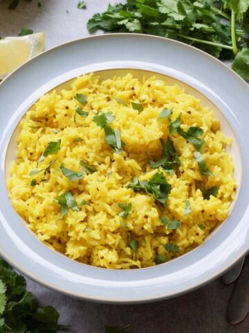 Bowlful of turmeric rice garnished with fresh coriander.