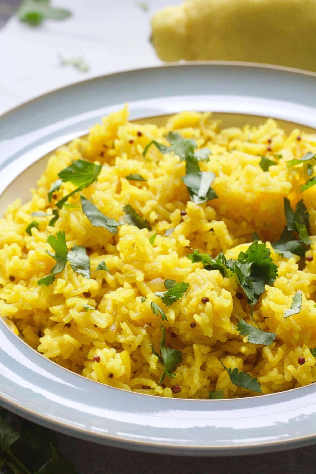 Yellow rice in a bowl with coriander garnish.