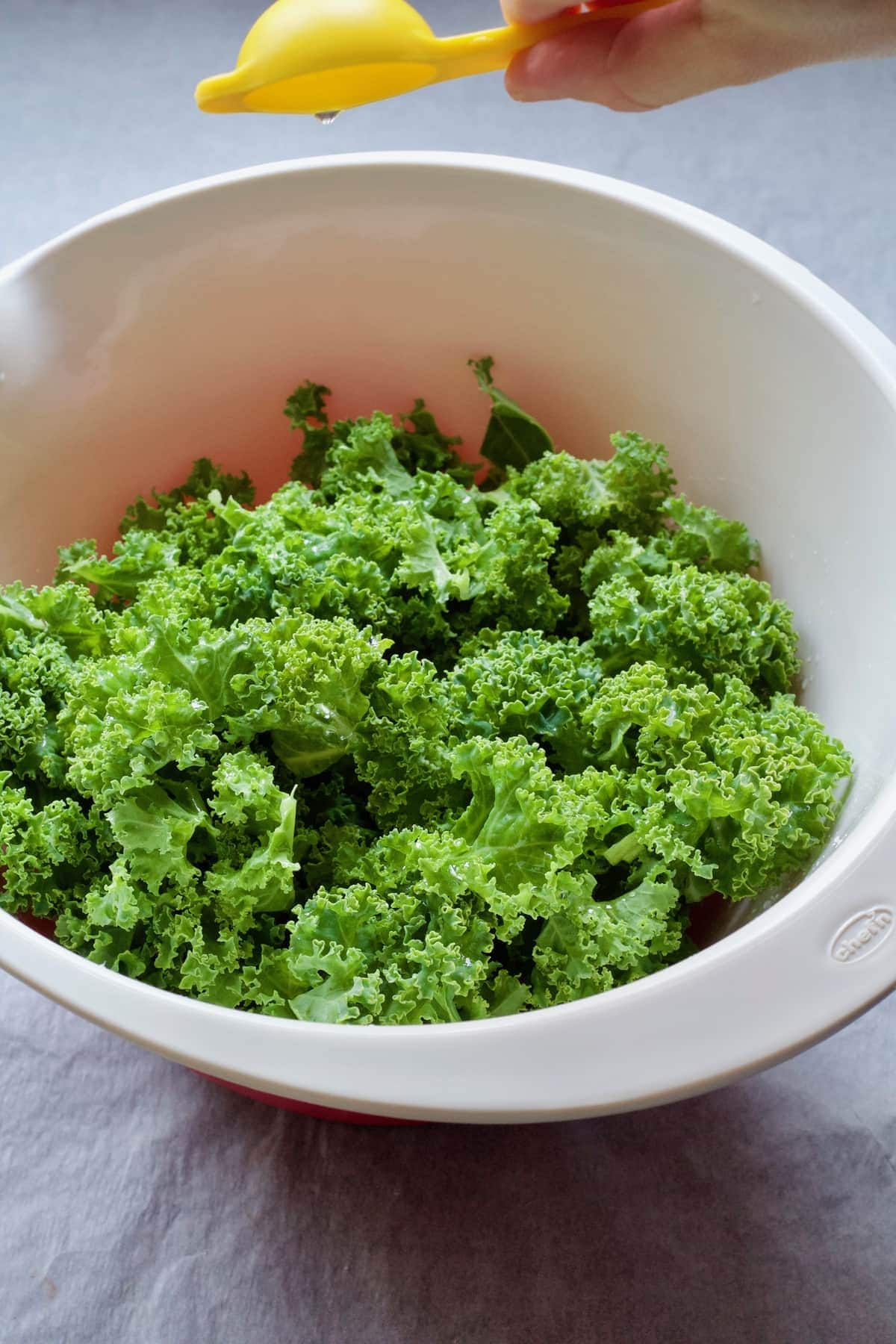 Pouring oil over greens in a bowl.