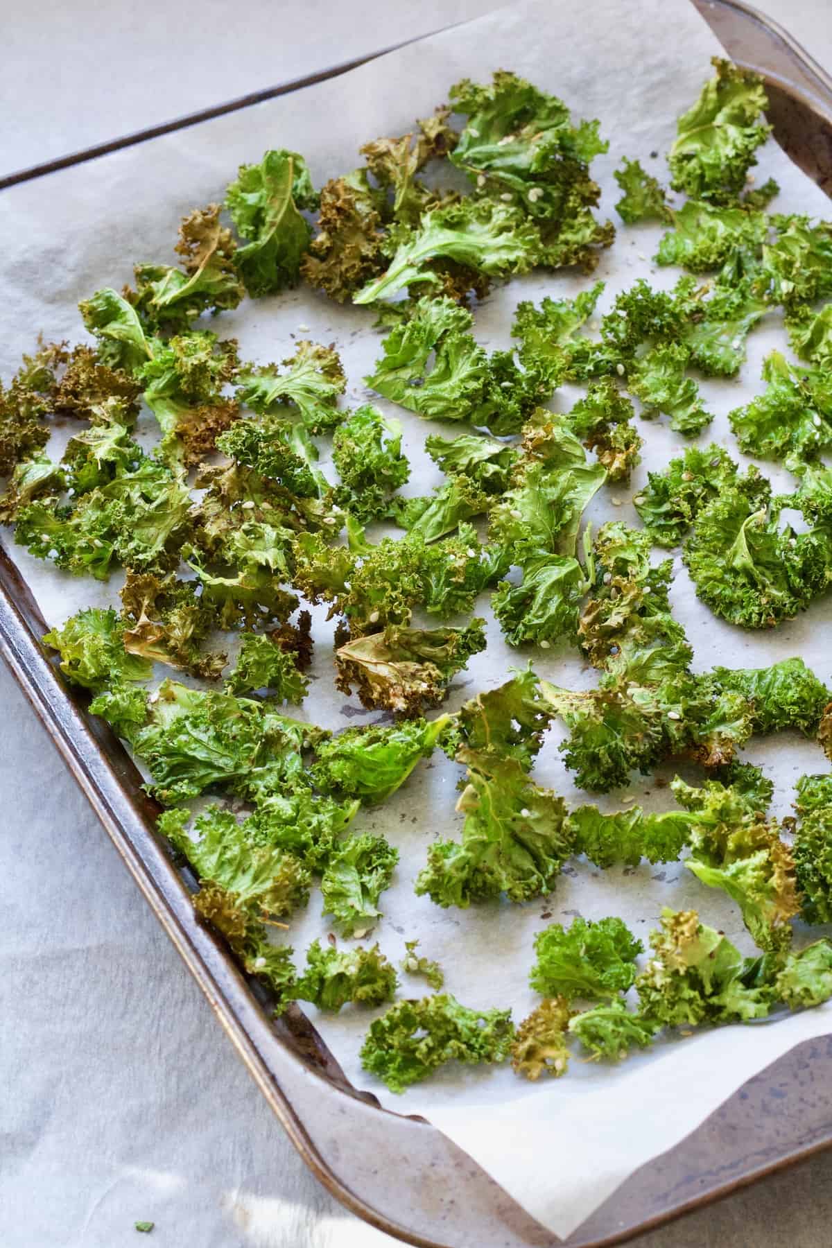 Baked kale crisps on a baking tray.