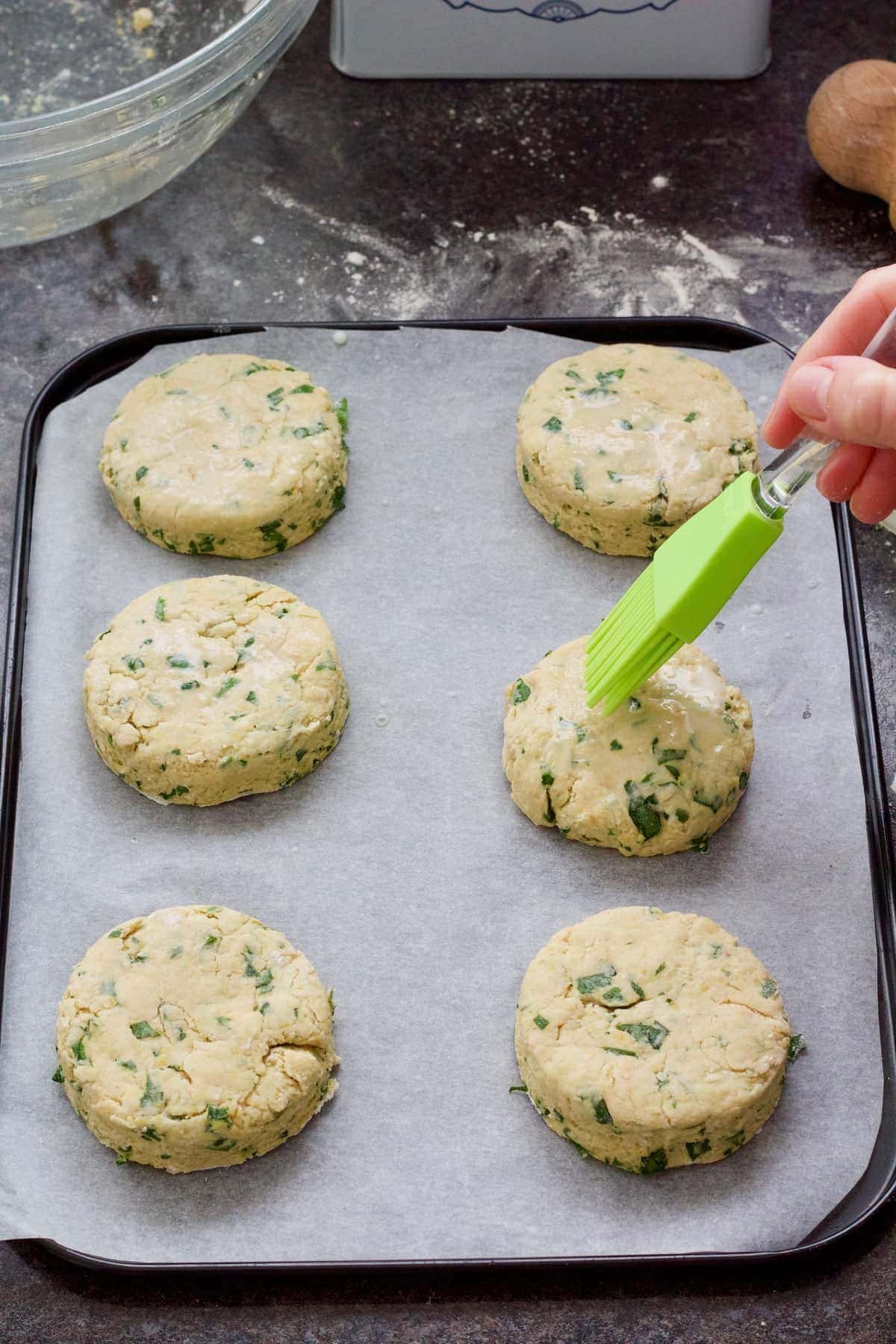 Brushing unbaked scones with plant milk.