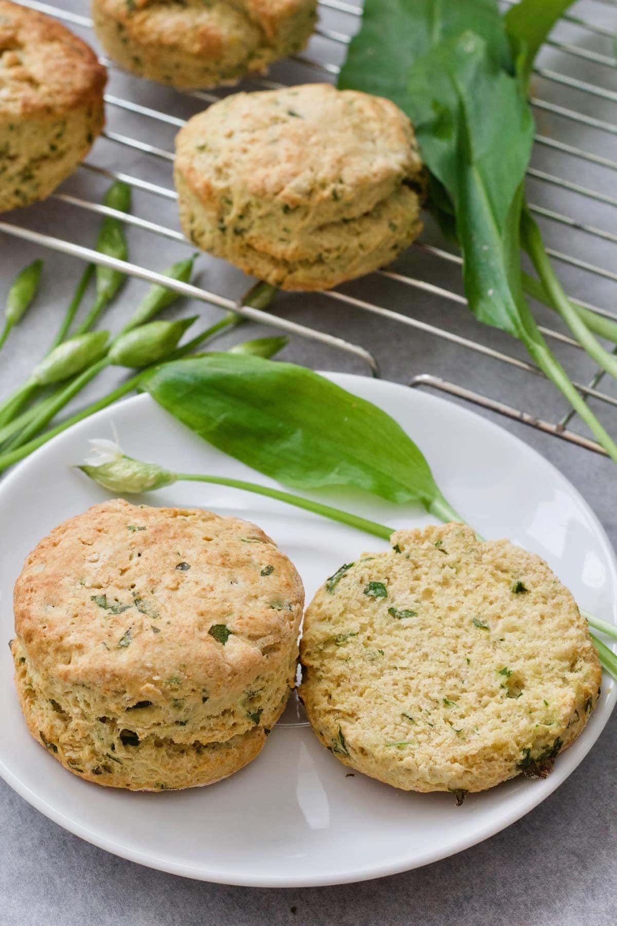 Scone & a half on a plate with wild garlic leaf & flower.