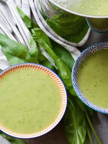 Wild garlic soup in bowls with leaves around.