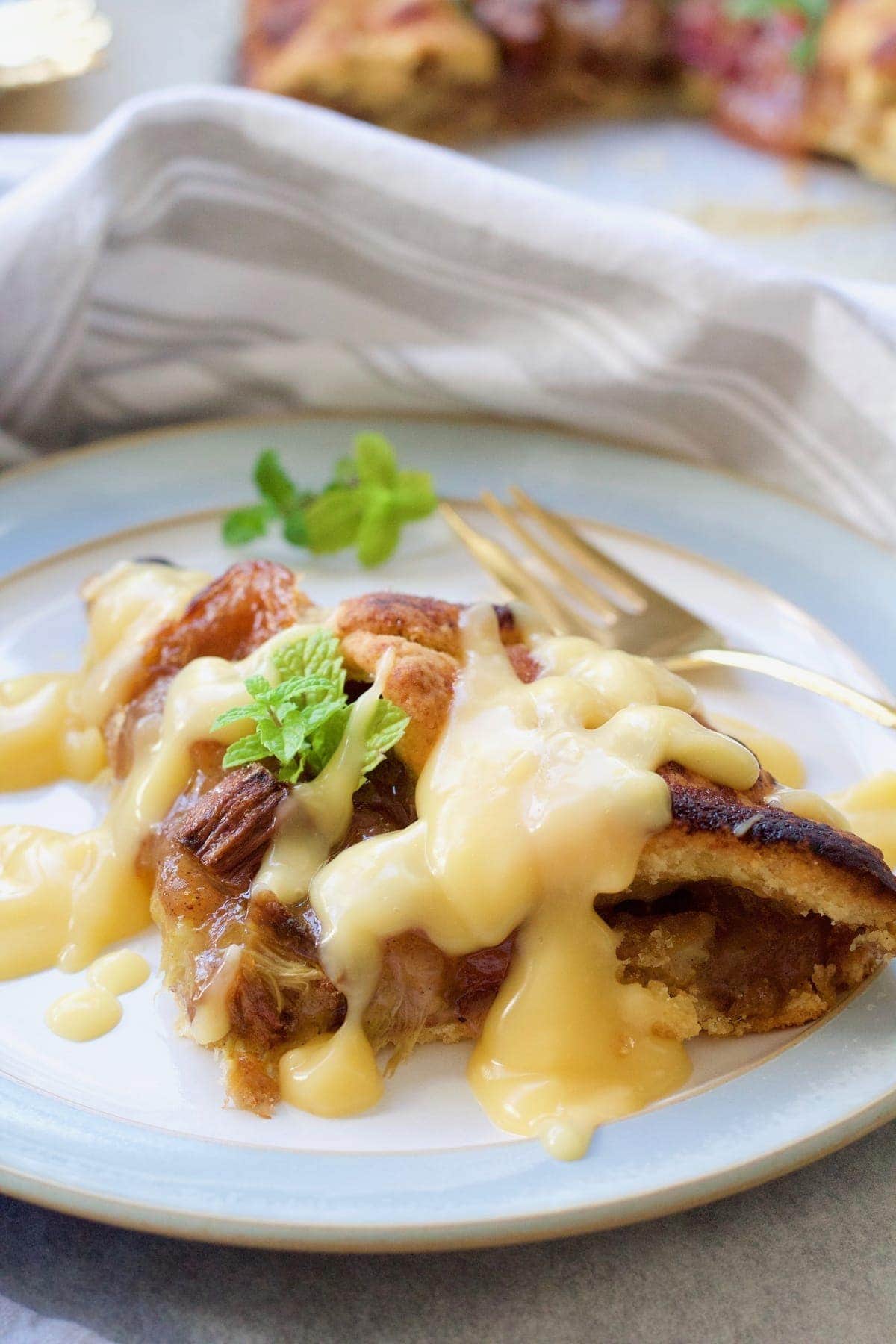 Slice of galette on a plate with custard & fork on a side.