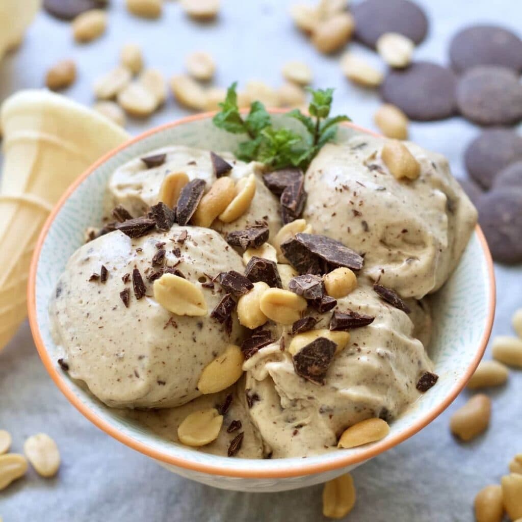 Close up of bowl of banana ice cream with peanuts & chocolate.