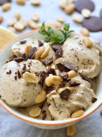Close up of bowl of banana ice cream with peanuts & chocolate.