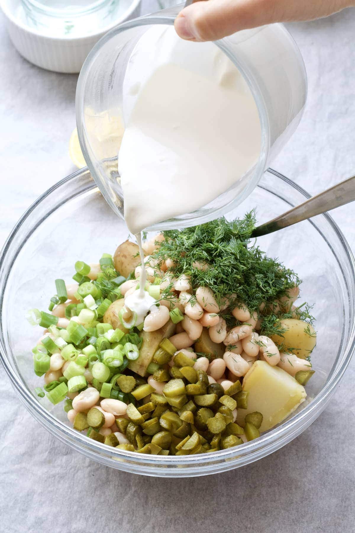 Pouring dressing over salad ingredients.