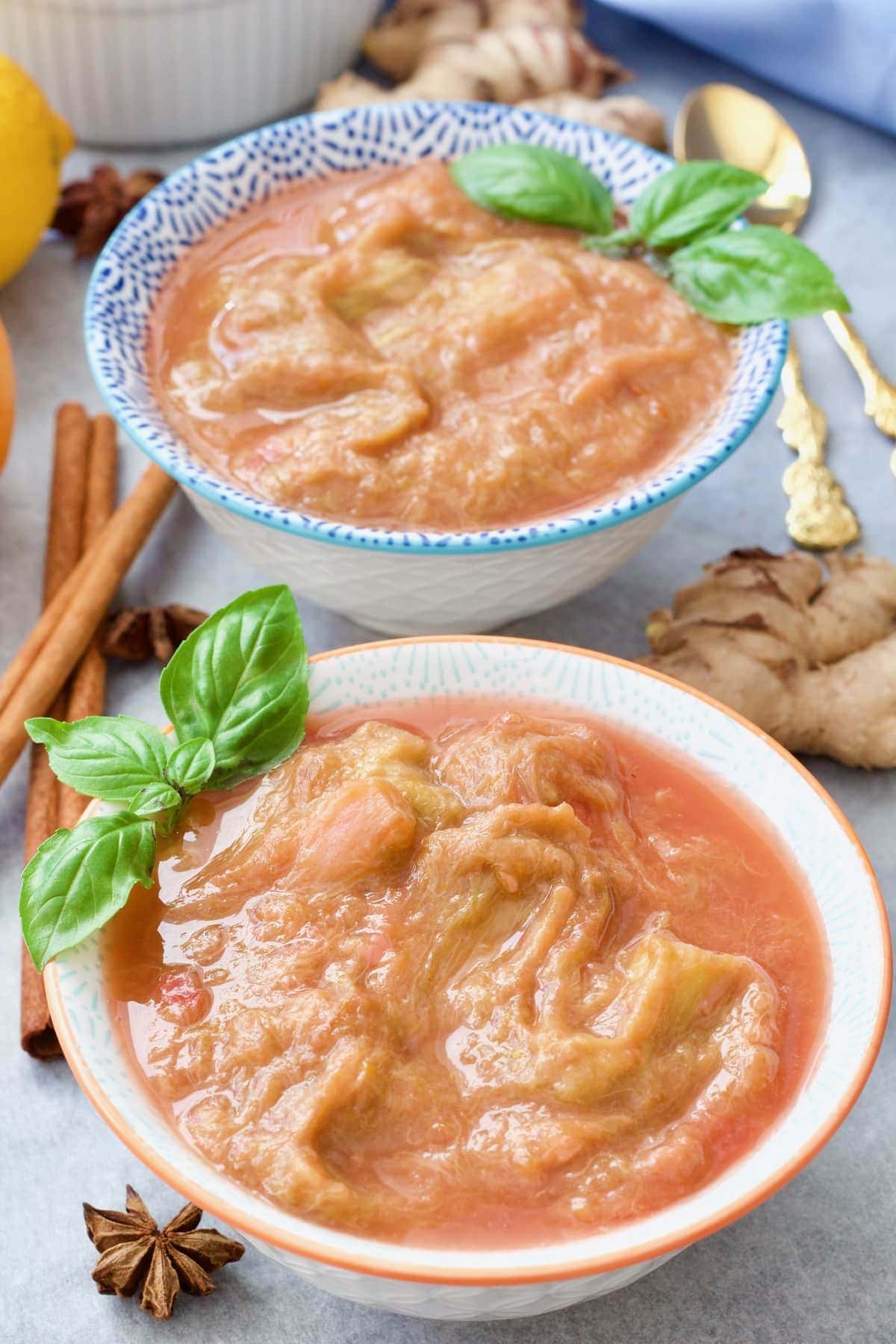 Two bowls of stewed rhubarb with basil garnish.