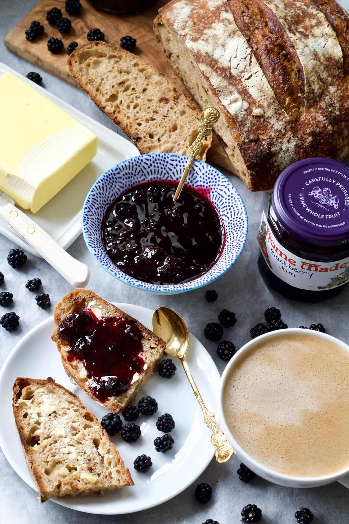 Breakfast spread with bread, blackberry jam, butter, coffee.