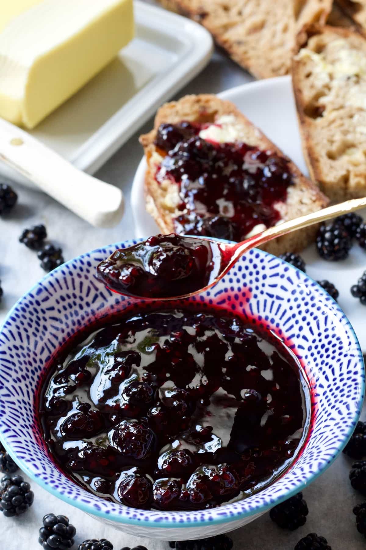 Spoonful of blackberry jam over a bowl filled with jam.