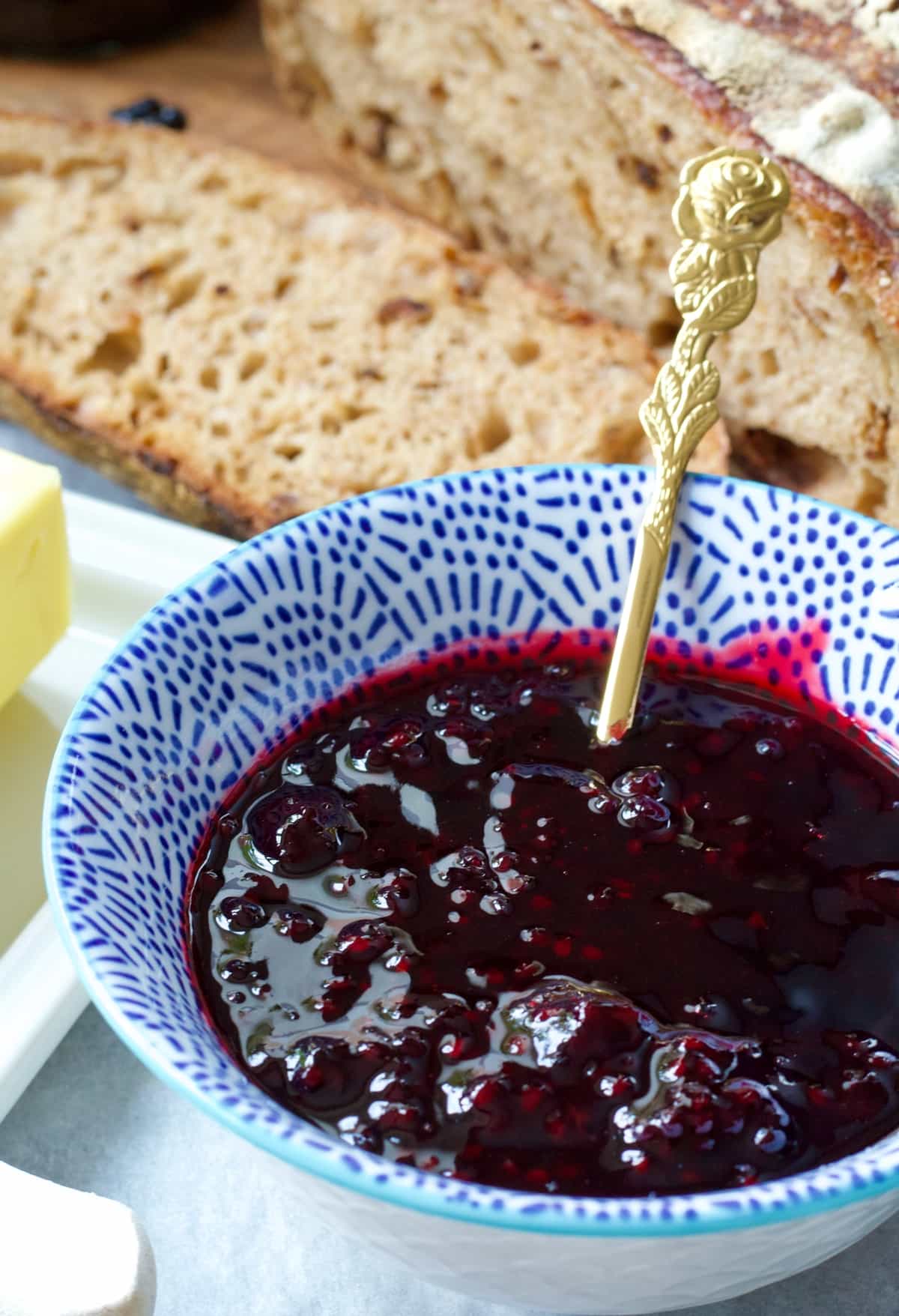 Bowl of blackberry jam with spoon in it.