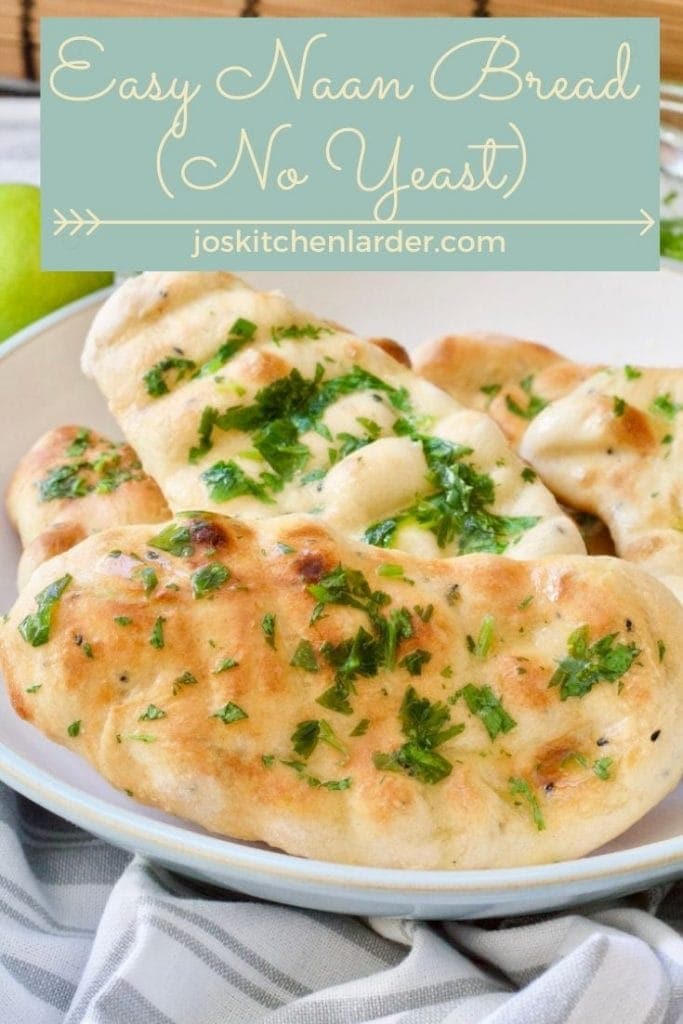 Cooked naan bread in a bowl brushed with herb butter.