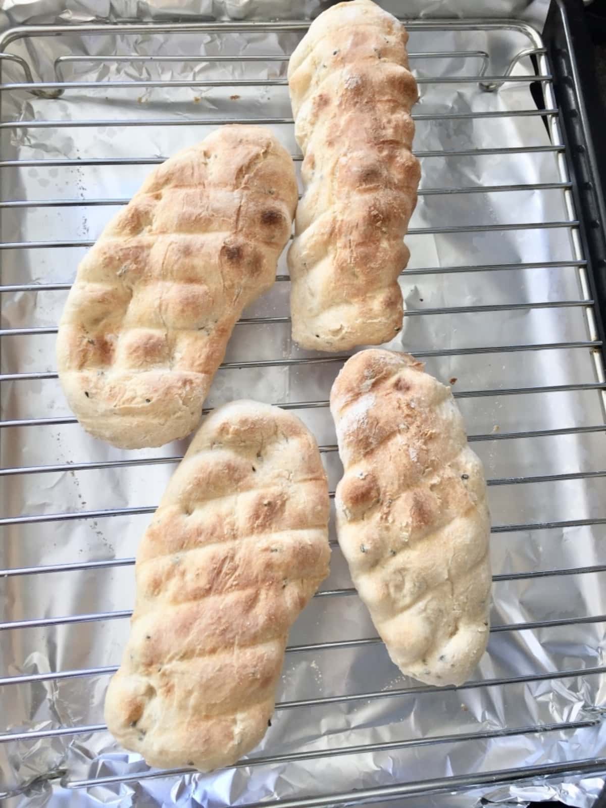 4 cooked naan breads on a grill rack.