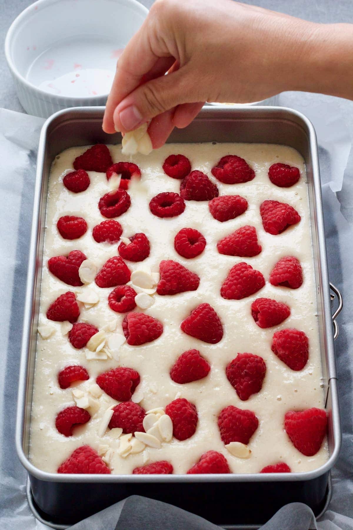 Hand sprinkling flaked almonds on top of the unbaked cake.