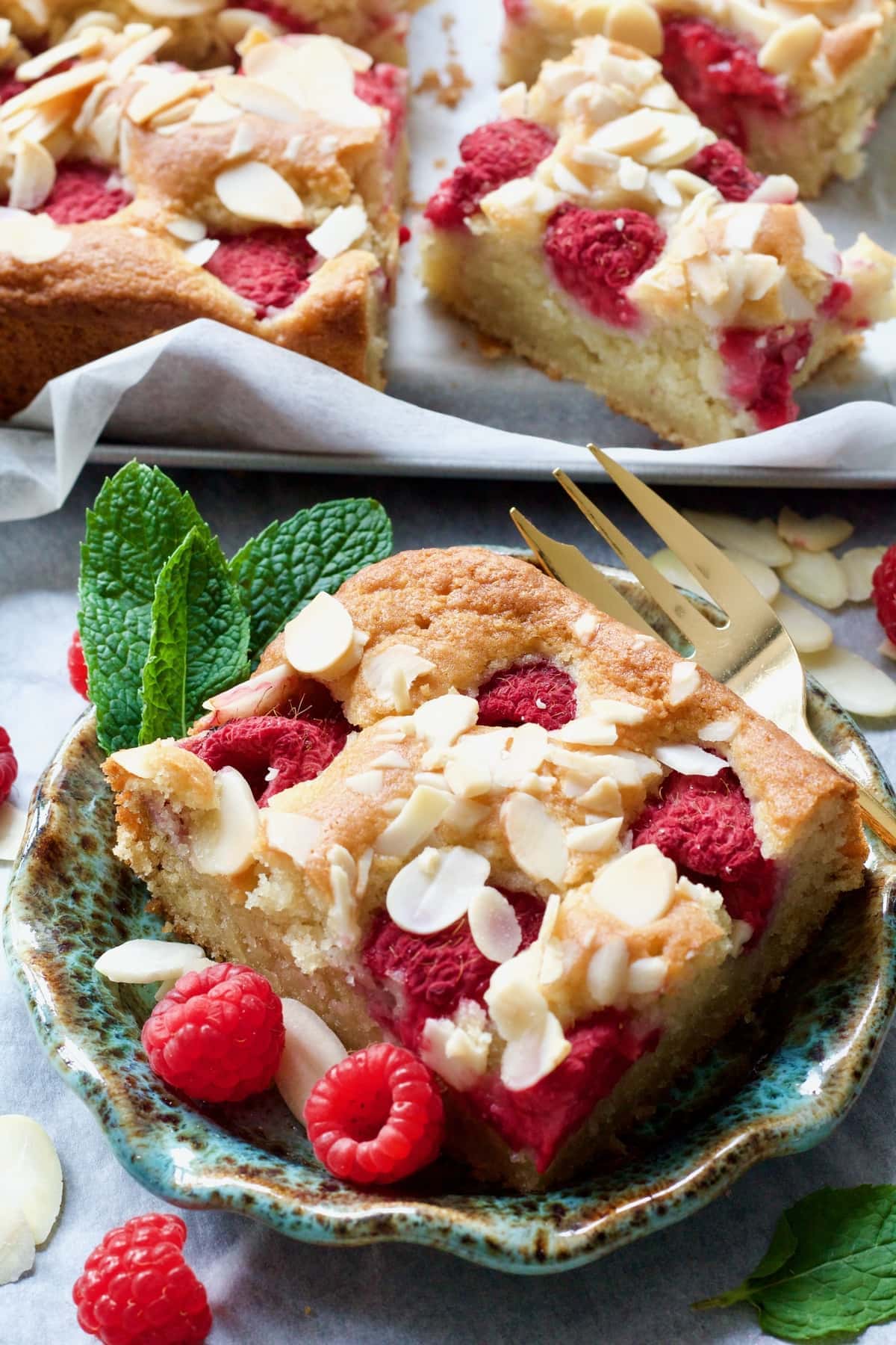 Slice of raspberry cake on a plate with a fork.