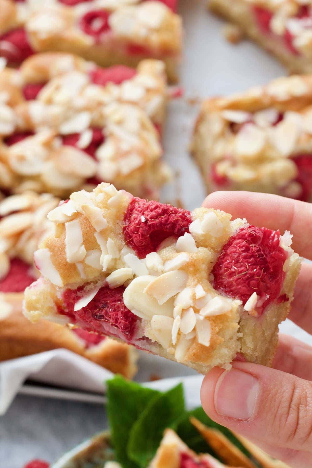 Hand holding small slice of raspberry cake.